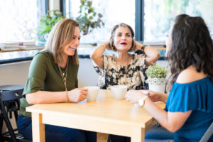 Kolme naista keskustelee kahvin ääressä.