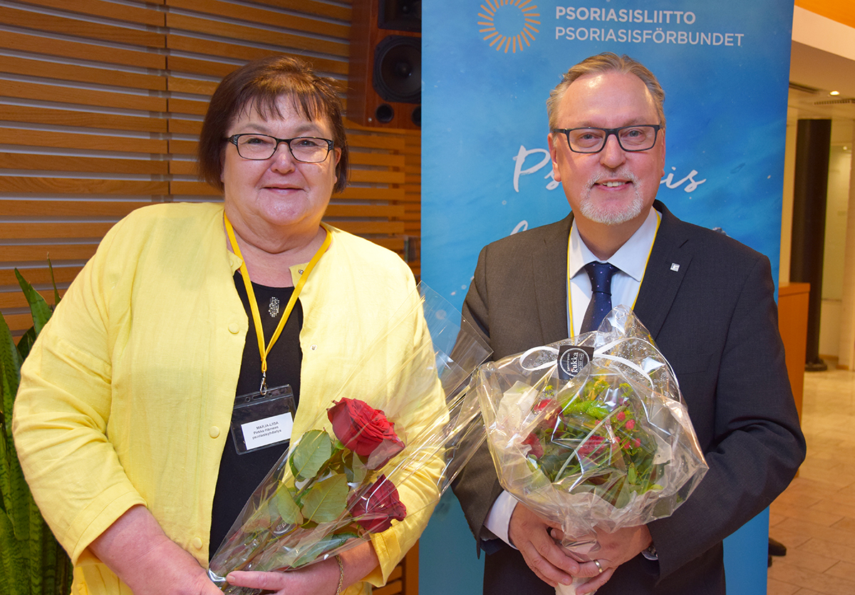 Psoriasisliiton puheenjohtaja Antero Laukkanen ja varapuheenjohtaja Marja-Liisa Utukka kukat kädessään.