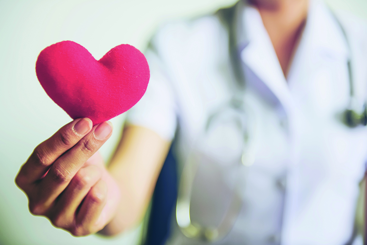 Terveydenhuollon ammattilainen pitää kädessään punaista sydäntä.