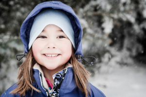 Lapsi hymyilee talvimaisemassa.