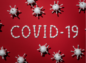 Koronaviruksia ja teksti Covid-19 punaisella taustalla.