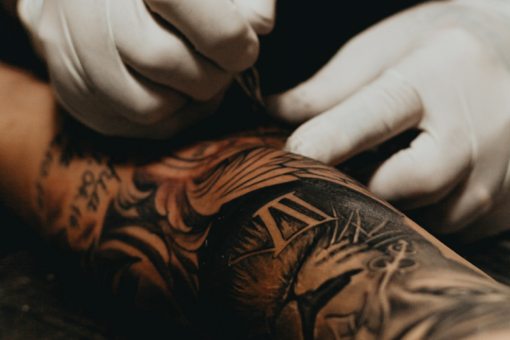 Tatuoija tekee käsivarteen tatuointia mustalla värillä.