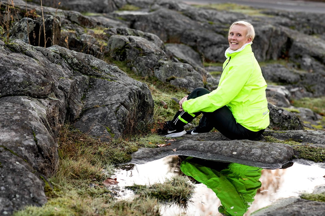 Fysioterapeutti Seija Mustonen istuu kalliolla.