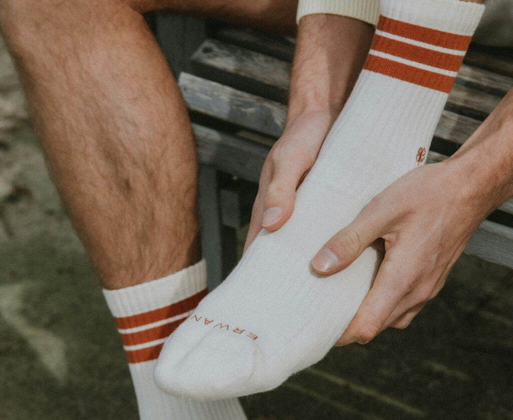 Mies istuu penkillä ja pitelee jalkateräänsä.